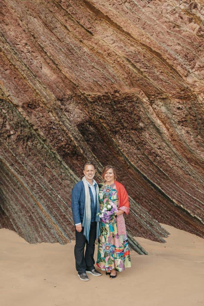 Couple posing for a photo on La Concha Beach in San Sebastian, whilst eloping in a public space in Spain for their celebrant vow renewal ceremony officiated by Marcia Bravo Celebrant UK and Spain..  